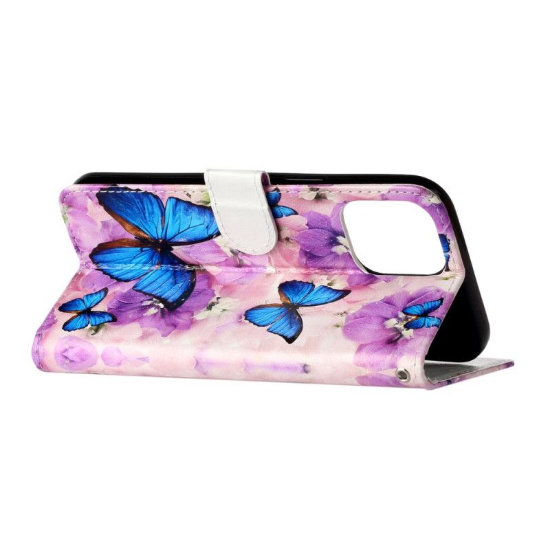 Folio-hoesje iPhone 16 Pro Telefoonhoesje Blauwe Vlinders En Paarse Bloemen Met Riempje